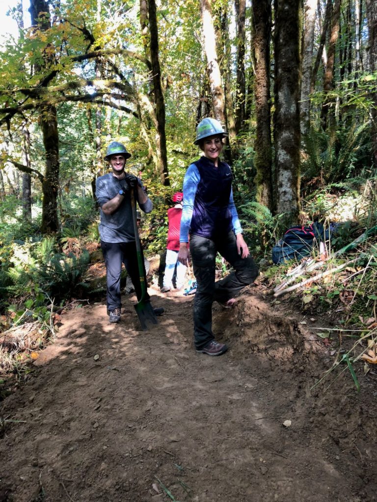 Two volunteers showing off their hard freshly benched trail.